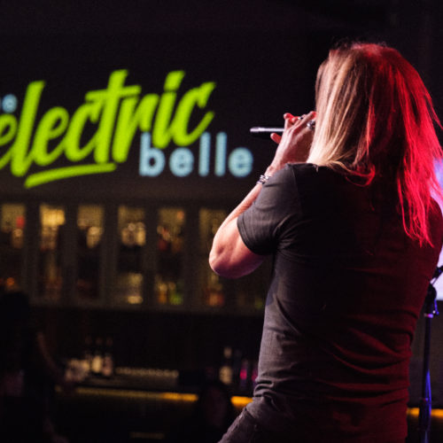 band vocalist in front of Electric Belle logo